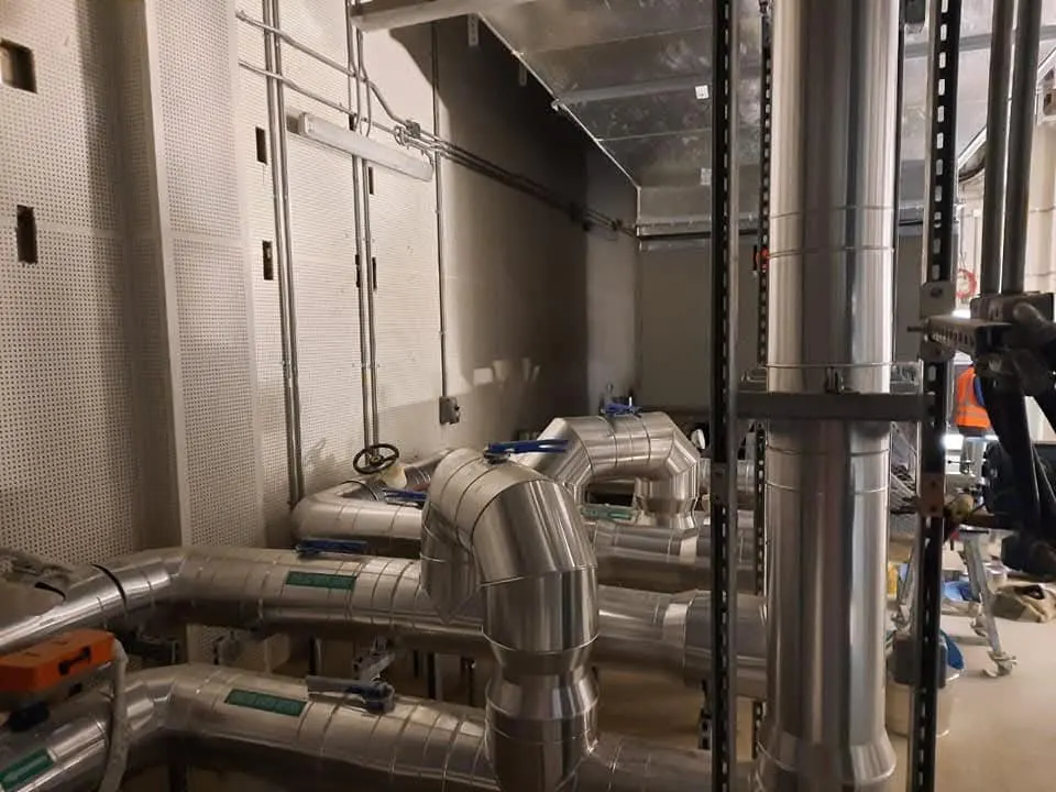 Technicians inspecting ducting inside a large industrial building