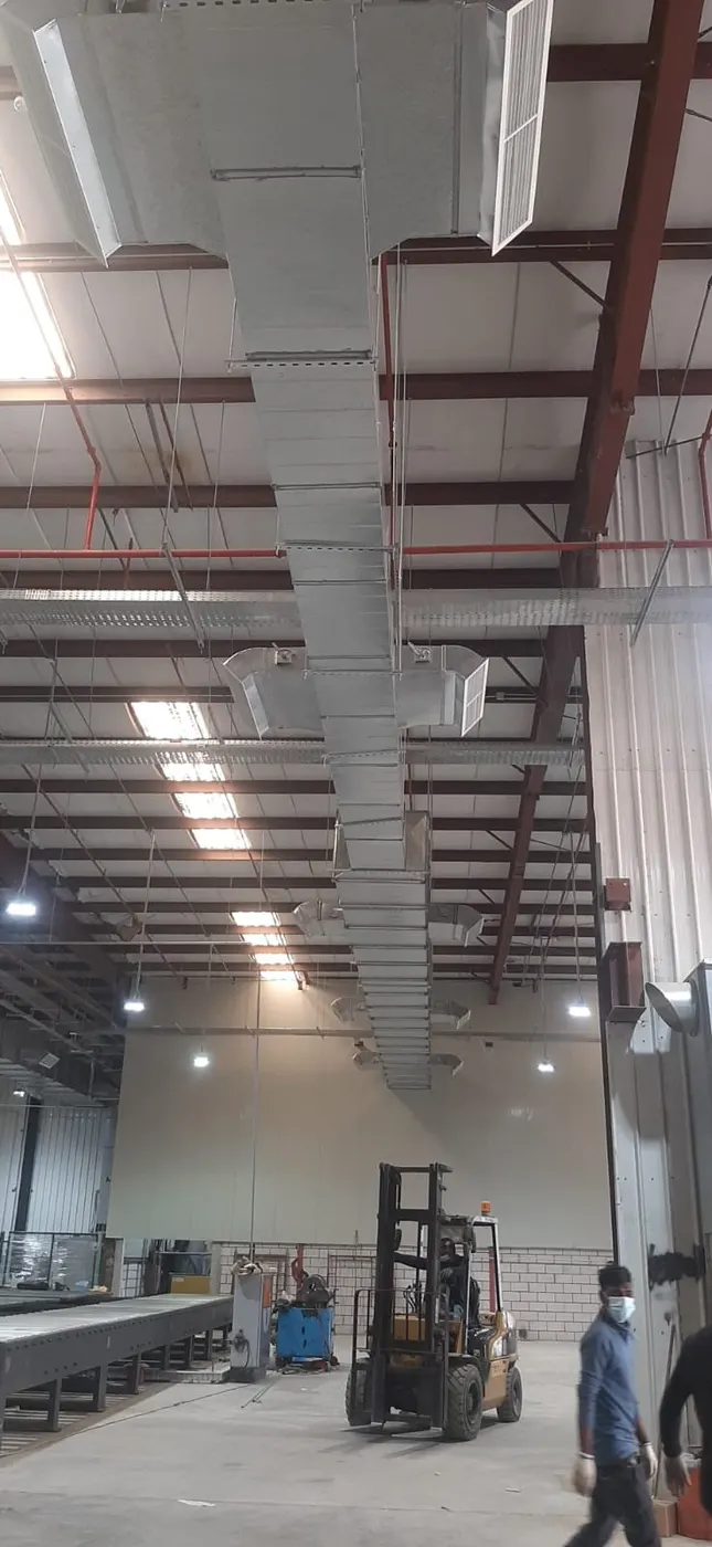 Vertical duct run beside a warehouse wall with a forklift below